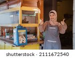 Small photo of proud muslim woman with her small food stall thumb up