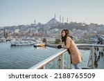 asian woman leaning on a bridge looking at panoramic view of beautiful city of instanbul and bosphorus in turkey