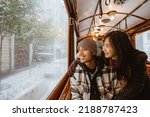 Small photo of Portrait of young asian man and woman looking at the snow through train window. couple passenger riding classic train during their trip in turkey