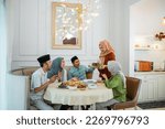 Small photo of muslim woman serving drink for her friend and family at home having dinner together