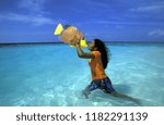 Small photo of a women of the Maldives poses with a woodfish on a beach with the seascape of the island and atoll of the Maldives Islands in the indian ocean. Indian Ocean, Maldives, February, 2003