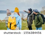 Small photo of Embark on an adventure Happy five friends getting ready for travel. Women and men choose a travel route. Late autumn mood, beautiful lake on background. Friendship trip, travel, destination concept