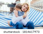 Small photo of Mother laying on the hammock hugging her child. Single mom becalm son while relaxing in hammock at terrace outdoor. Lifestyle,holiday, caressing concept.