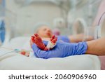 Macro photo of doctor's hands and legs of a child. Newborn is placed in the incubator. Neonatal intensive care unit