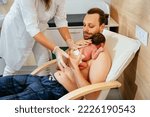 Small photo of Nurse or doctor in gloves help new american father taking care of his premature baby doing skin to skin at hospital in post natal department.