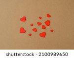Many small wooden red hearts on a kraft paper background. Love background, Valentine`s day concept 