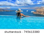 Woman enjoying relaxation in pool and looking at the view in Santorini Greece