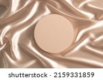 Geometric platform podium on pastel wave silk satin fabric background. Blank minimal cylinder form mock up background for beauty cosmetic product presentation. Top view, copy space