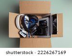 Small photo of Cardboard box full of old used laptop computers, digital tablets, smartphones, power bank for recycling on gray background. Donation, e-waste, electronic waste for reuse, refurbish and recycle concept