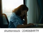 Small photo of woman sitting down, his face unsettled. At the computer desk she has headaches and stress. Cause of hard work and insufficient rest.