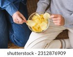 Closeup image of friends sharing and eating potato chips together