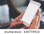 Mockup image of hand holding mobile phone with blank white screen in vintage cafe