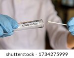 Medical worker holding swab sample collection kit, test tube for performing patient nasal swabbing. Hands in gloves holding testing equipment for Coronavirus COVID-19 diagnostic.