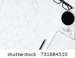 Business desk composition. Notebook, pen, glasses, paperclip, hot coffee on marble table. Modern workspace for businessman working concept. Flat lay, top view. B&W tone. Copy space.