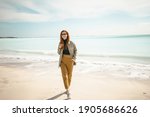 young beautiful red-haired girl walking on the beach near the ocean