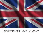 Great britain flag with big folds waving close up under the studio light indoors. The official symbols and colors in fabric banner