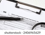Small photo of Form 990 Return of organization exempt from income tax on A4 tablet lies on office table with pen and magnifying glass close up