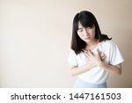 Small photo of Young woman suffering from chest pain over white background. Cause of chest pain inclued heart attack, angina, pericarditis, pulmonary embolism, heartburn, GERD or muscle strain. Health care concept.