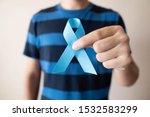 Small photo of Men's health and Prostate cancer awareness campaign in November month. Close up of young man hands holding light blue ribbon awareness. Symbol for support men who living with cancer.