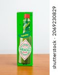 Small photo of Pruszcz Gdanski, Poland - July 31, 2021: Box of milder jalapeno Tabasco sauce on wooden table. McIlhenny Co Green pepper sauce.