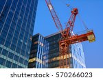 The crane against modern buildings under construction at dusk.