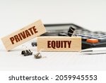 Small photo of Business and finance concept. On a white background, a calculator, a pen, reports and wooden dies with the inscription - Private Equity
