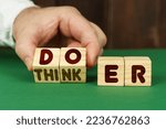 Small photo of Business concept. On a green surface, a man puts cubes with the inscription - DOER, THINKER