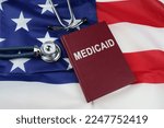 Small photo of Law concept. On the US flag lies a stethoscope and a book with the inscription - Medicaid