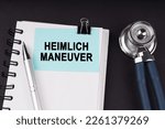 Small photo of Medical concept. On a black surface, a stethoscope, a notebook, a pen and a blue sticker with the inscription - HEIMLICH MANEUVER