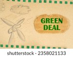 A wind generator and clouds are drawn on cardboard with green holes, next to it lies a cardboard with the inscription - Green Deal. Ecological concept.