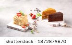 Small photo of Desserts. Cakes: Napoleon, honey cake and chocolate cake on light wooden boards on a light gray table. Fresh berries, strawberries and mint, spoon. Background image, copy space, horizontal