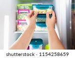 Woman placing container with frozen mixed vegetables in refrigerator.
