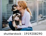 Young adult woman holding adorable dog in animal shelter.