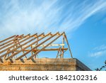 Wooden rafters against the blue sky in house under construction. Installation of rafters on the roof of a house under construction against the background of the sky