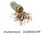 Black allspice ground pepper is scattered from a pepper pot on a white background.