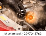 Small photo of Auto mechanic hand opens the radiator cap with steam escaping around the engine compartment from the high heat,water temp gauge symbol with high temperature,Car maintenance service concept.