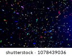 Thousands of confetti fired on air during a festival at night. Image ideal for backgrounds. Multicolor are the confetti in the picture. The sky as background is black. Cold tonality