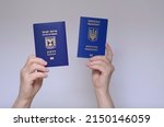 Small photo of The concept of changing citizenship. Repatriation. Law of Return. Women's hands holding an Israeli passport and a Ukrainian passport on a white background