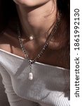 Small photo of Necklace consisting of a large weave silver chain with a pendant from a baroque pearl of an elongated shape on a girl in a sweatshirt. Gift, decoration, pearls, wedding, christmas, jewerly