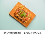 Authentic mexican chicken and beef tacos. Three tacos served on a wooden board over pastel blue mint background. Traditional mexian food, delicious dish. Copy space banner.