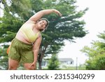 Small photo of Young pretty teeth smiling plus size Asian woman in Green sporty top and short doing exercise or streching in summer morning outdoor at park. Healthy and wellness concept wit fat girl.