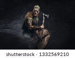 Small photo of Medieval warrior berserk Viking with tattoo and in skin with axes attacks enemy. Concept historical photo