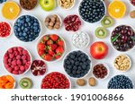 Fresh berries, fruits, nuts on a white wooden background. The concept of healthy eating. Food contains vitamins and trace elements