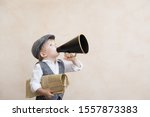 Child holding loudspeaker and newspaper. Kid shouting through vintage megaphone. Business news concept