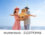 Happy family having fun on the beach. Mother and father holding son against blue sea and sky background. Summer vacation concept