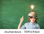 Portrait of child in classroom. Child with toy virtual reality headset in class. Success, idea and innovation technology concept. Back to school. Kid against blackboard with copy space