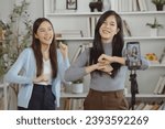 Small photo of A young female close friend stood and danced happily and relaxed, recording a live stream on her mobile phone at home. Two young women smile happily on holiday