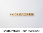 Small photo of Word Accredited made up of wooden blocks with lettering on white cardboard background. Minimum concept of Accreditation.