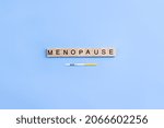 Small photo of Word menopause on wooden blocks with letters and rapid FSH test. Minimal concept of female periods. Copy space