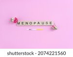 Small photo of The word menopause on wooden blocks with letters decorated with flowers and FSH test. Minimal concept of feminine periods.